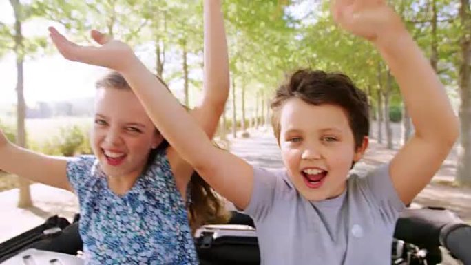 两个孩子站起来并挥舞着汽车天窗玩得很开心