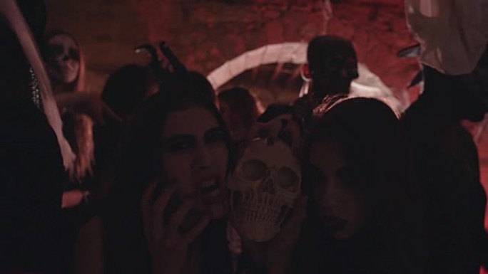 穿着哥特式万圣节服装的妇女在化妆派对上拿着头骨