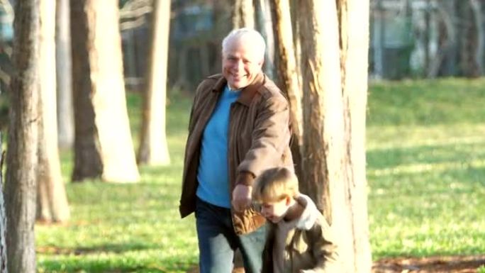 男孩拉着他的祖父，在公园散步
