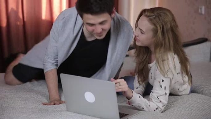 夫妇在家里的沙发上使用笔记本电脑