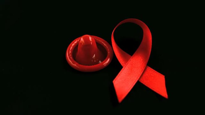 艾滋病红丝带符号掉落在避孕套旁边