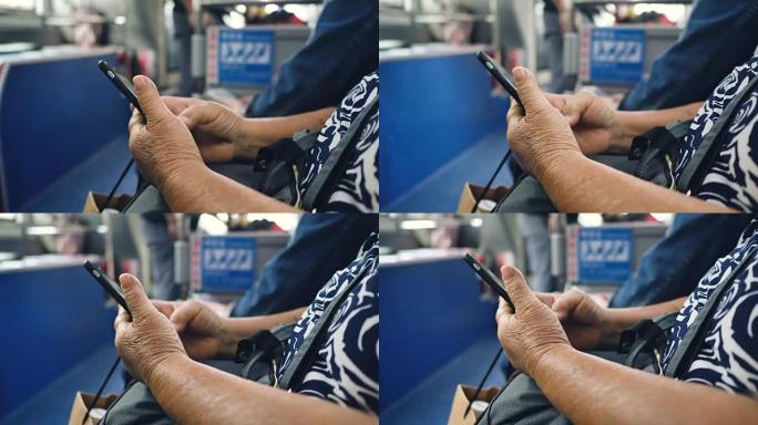 老年妇女在公共汽车上的乘客座位上使用智能手机
