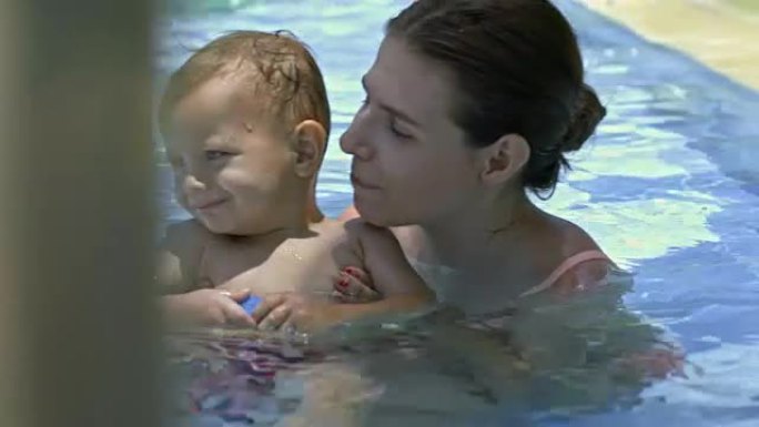 快乐的妈妈和小儿子在游泳池里交往