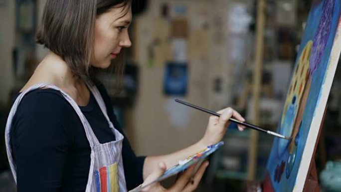 年轻艺术家女人在艺术学校的画布上画静物画