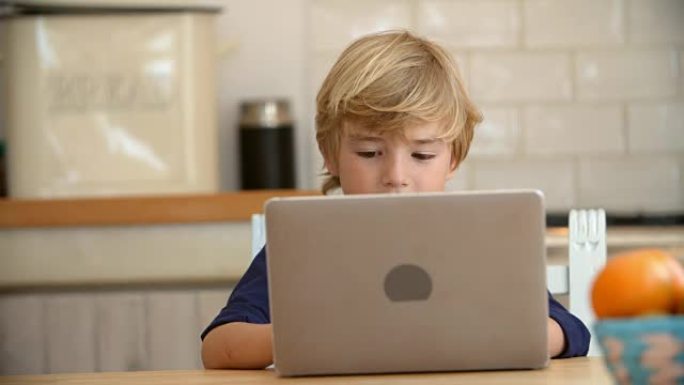小男孩在厨房的桌子上用笔记本电脑