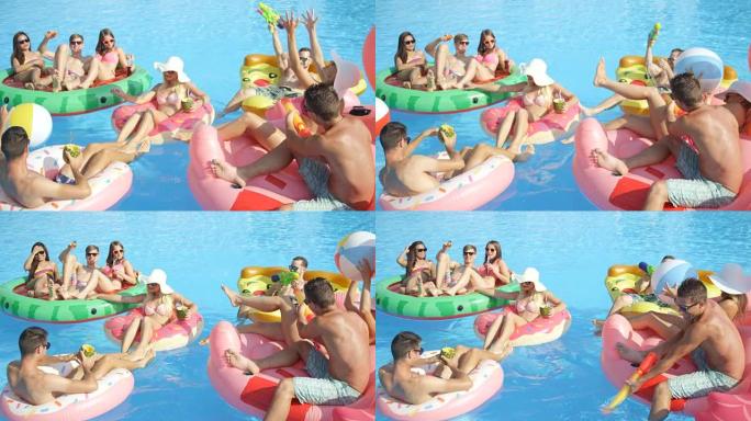 慢动作: 好玩的朋友在游泳池里有趣的五颜六色的漂浮物上打架