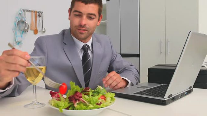 商人在吃饭时在笔记本电脑上工作