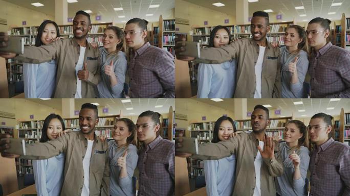 一群国际学生在大学图书馆的智能手机相机上微笑并制作自拍照片。快乐的朋友一起休息