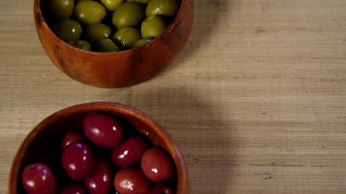红色和绿色的橄榄放在柜台上的碗中