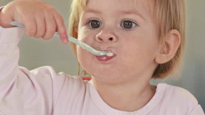 高清: 可爱的女婴用勺子吃饭