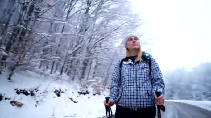 Female hiker walking on a road by the snowy forest