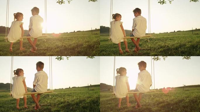 慢动作特写激动的年轻男孩和女孩在日落时在木头秋千上聊天