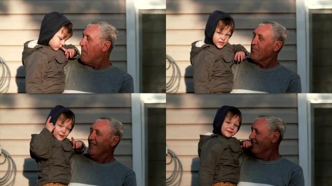 老人手握小男孩。祖父和孙子说话，微笑着，看着户外的阳光。4K