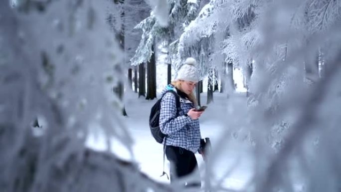 Beautiful female hiker using smart phone in winter
