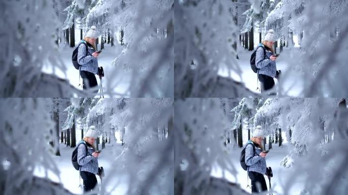 Beautiful female hiker using smart phone in winter