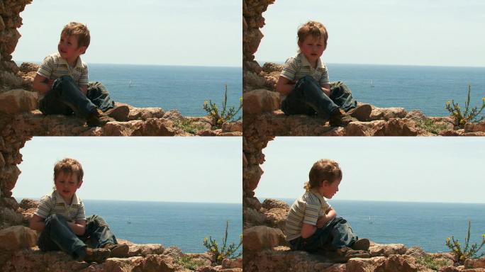 小男孩坐在古老的废墟上