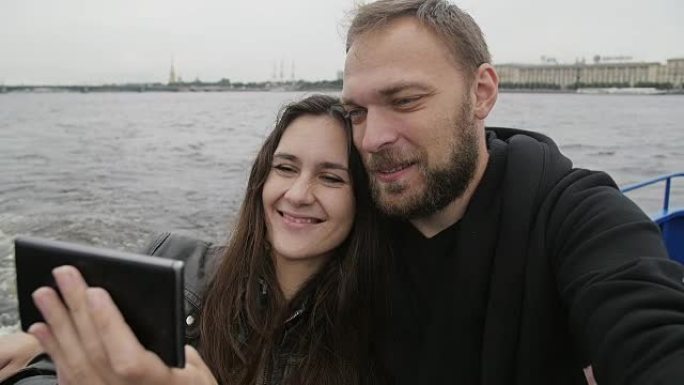 恋爱中的幸福夫妻，微笑，自拍。恩爱的夫妇使用智能手机在缓慢的圣彼得堡进行自拍照