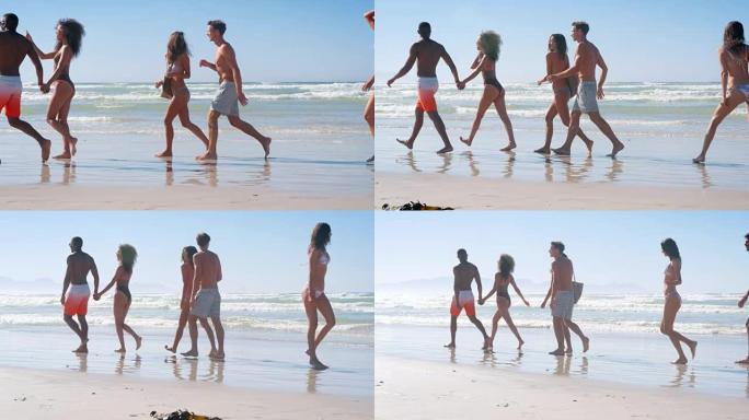 一群朋友在海滩度假时沿着海岸线散步