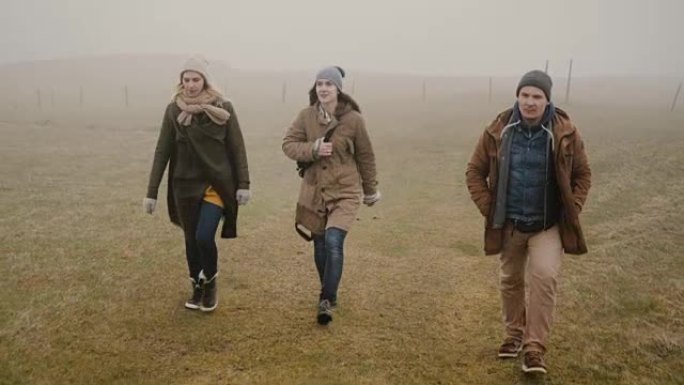 雾天一起徒步旅行的朋友。两个女人和男人一起探索冰岛，享受大自然