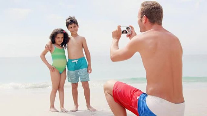 父亲在海滩上给孩子拍照