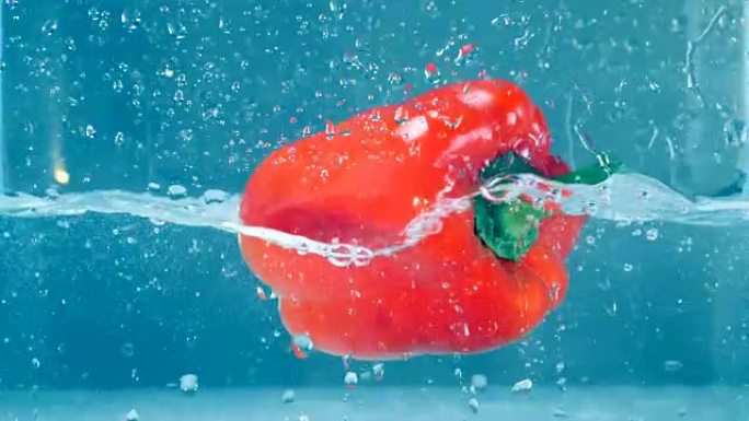 一个新鲜的红甜椒掉进清澈的水里。