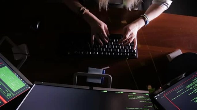 女人用手敲电脑代码，黑屋子里的电脑。工作中的黑客，程序员