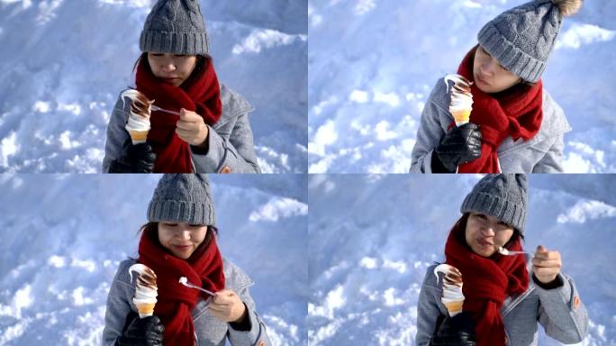 日本北海道小樽的快乐亚洲女人在雪地里吃冰淇淋