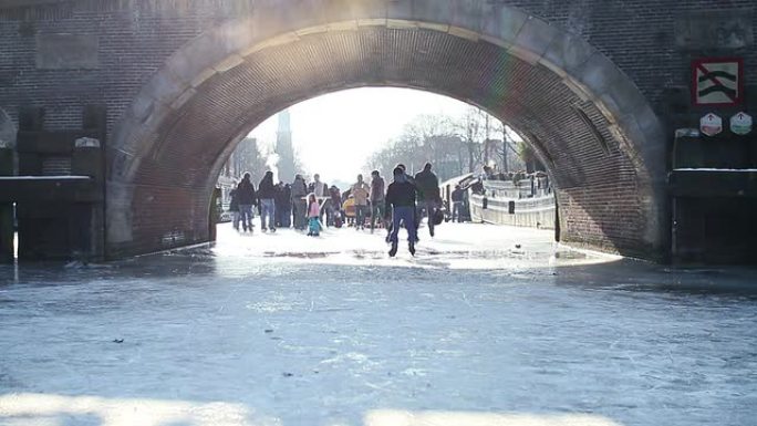 在桥下结冰的阿姆斯特丹运河上滑冰