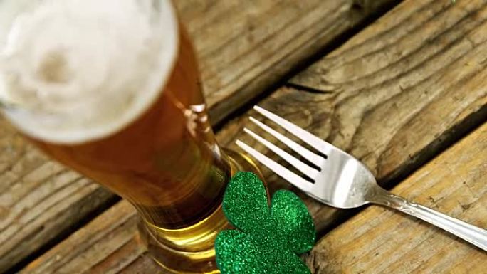 圣帕特里克木桌上一品脱啤酒、叉子和三叶草的特写视图