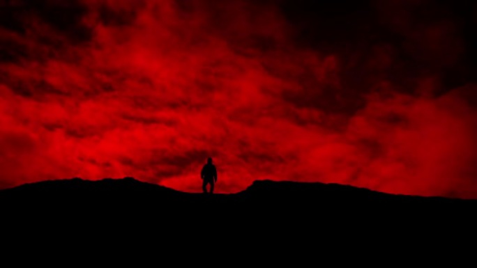 男子在红色的天空剪影上越过山坡