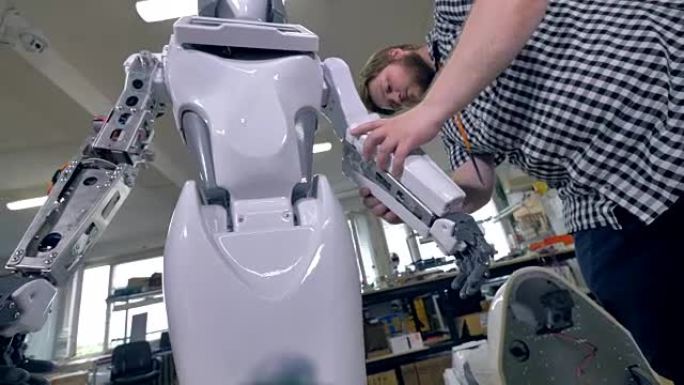 一个年轻的修理工在前臂上覆盖机器人钢架。