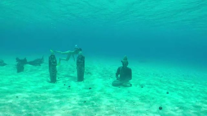 水下: 年轻女子在水下潜水，游泳并探索水晶般清澈的蓝色海洋泻湖中的海底沉没雕像