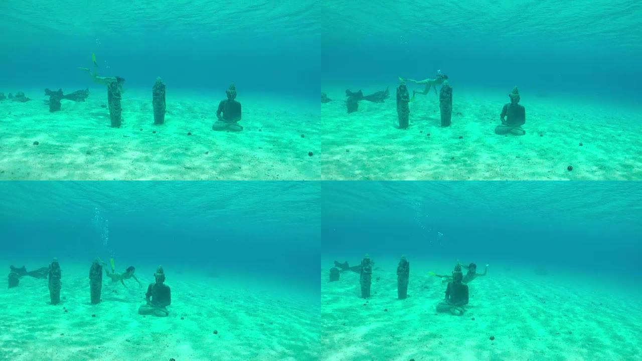 水下: 年轻女子在水下潜水，游泳并探索水晶般清澈的蓝色海洋泻湖中的海底沉没雕像