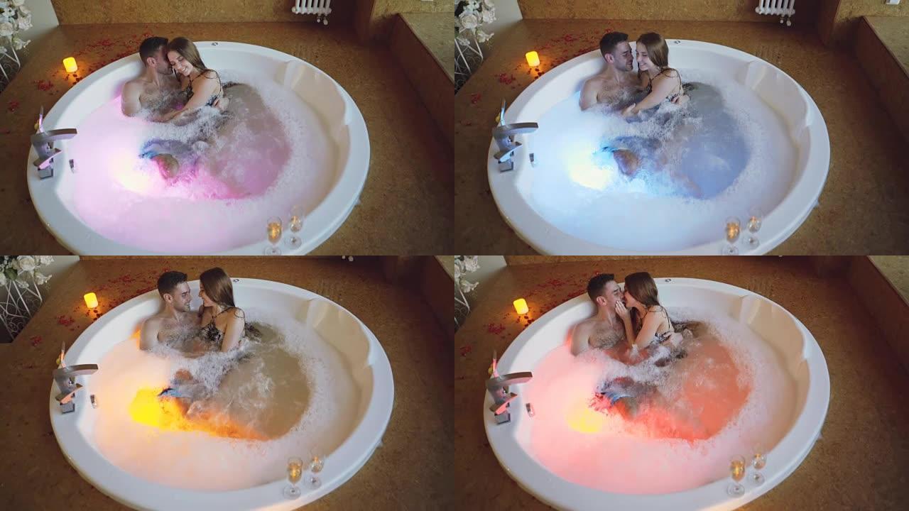 穿着泳衣的年轻人在日间水疗中心用泡沫在热水浴缸里聊天、拥抱和接吻的高角度视角。浪漫关系、激情和健康概