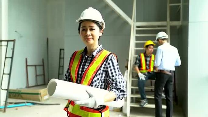 年轻的女性建筑专家在建筑工地拿着蓝图。