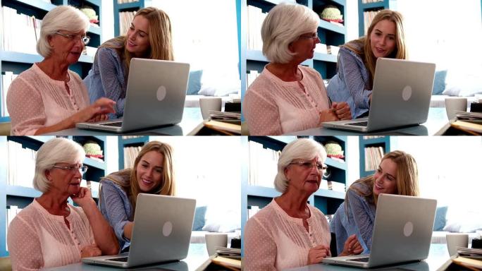 女儿在家里帮助年老的母亲使用电脑