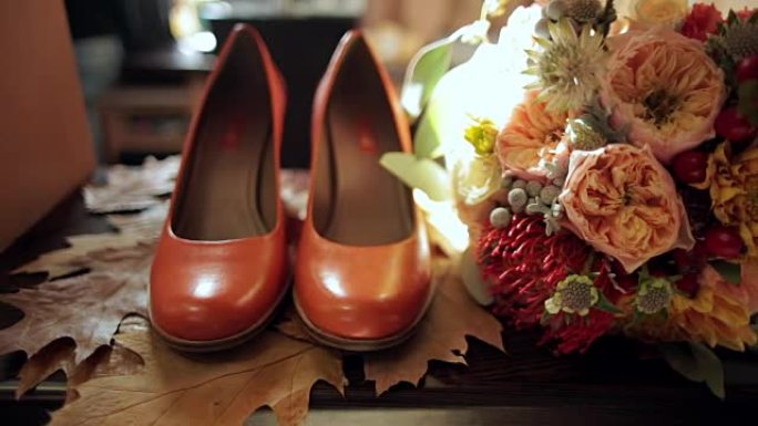 秋天的叶子上的新娘花束和新娘的鞋子