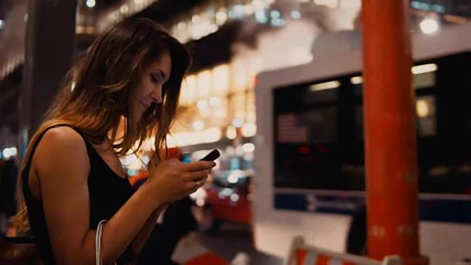 年轻快乐的女人，带着购物袋站在纽约市中心的烟雾管道附近，并使用智能手机