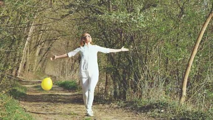 SLO MO开朗的女人在森林里跳气球