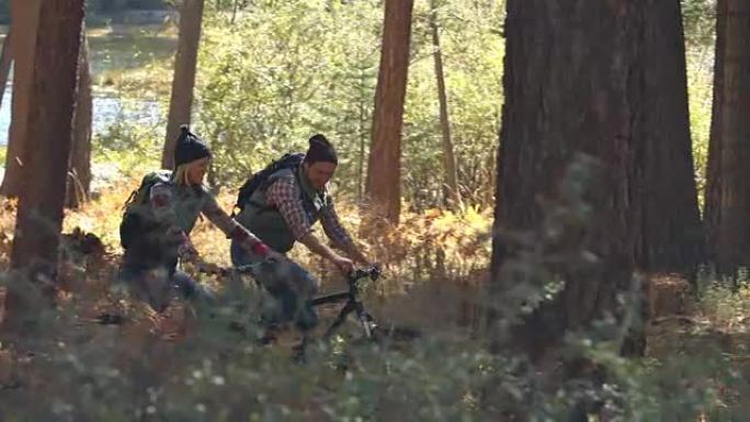 情侣在森林里聊天和骑山地自行车，平移镜头
