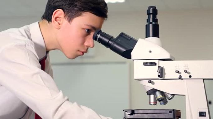 青少年在学校实验室学习生物学，通过显微镜观察。