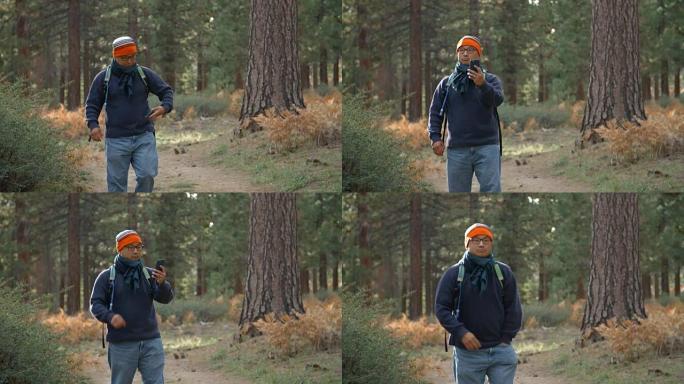 一名亚洲男子在森林里使用智能手机，正面图片