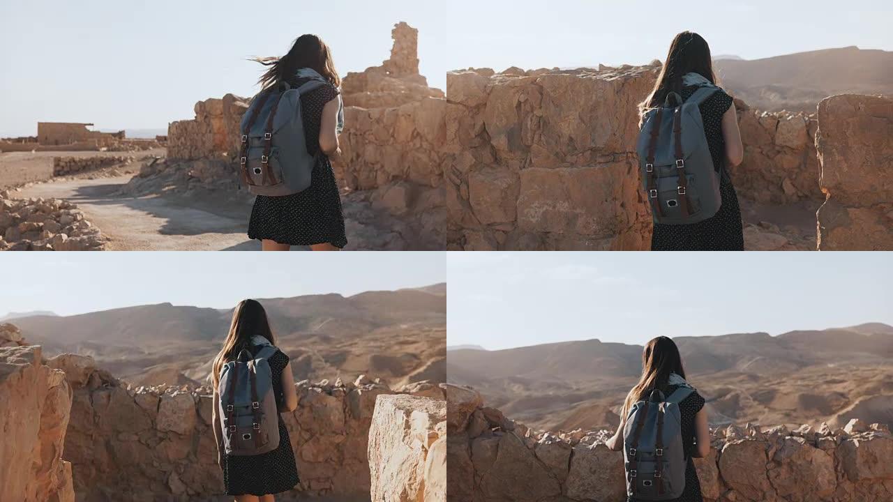 背着背包的女人走在古老的城墙之间。迷人的高加索女性游客喜欢山全景。马萨达。4K
