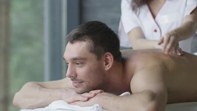 英俊的男人正在健康中心的女按摩师那里得到放松的按摩。