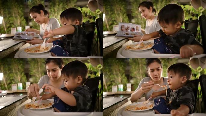 亚洲婴儿晚餐与年轻美丽的母亲在户外餐厅。