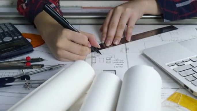 特写有吸引力的年轻女建筑师在办公桌前工作，并制定蓝图计划