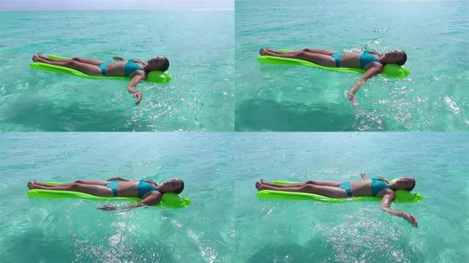 慢镜头:微笑的女人在漂浮在海洋中的气垫床上放松