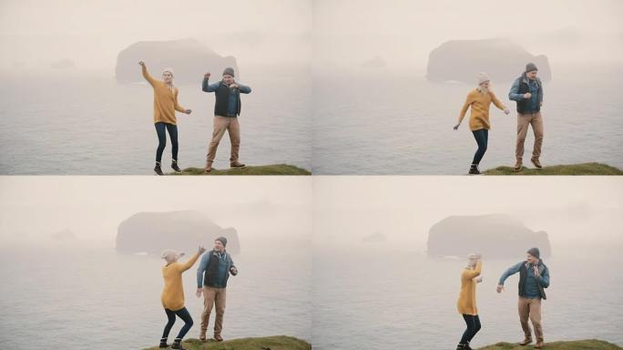 年轻幸福的夫妇在海边跳舞。游客在山上徒步旅行后，男人和女人一起玩乐