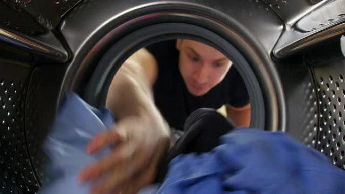 男子将衣物放入洗衣机