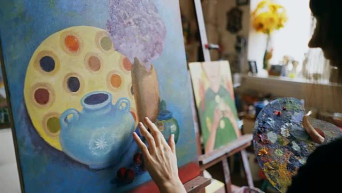 女艺术家在艺术工作室的画布上涂抹油画